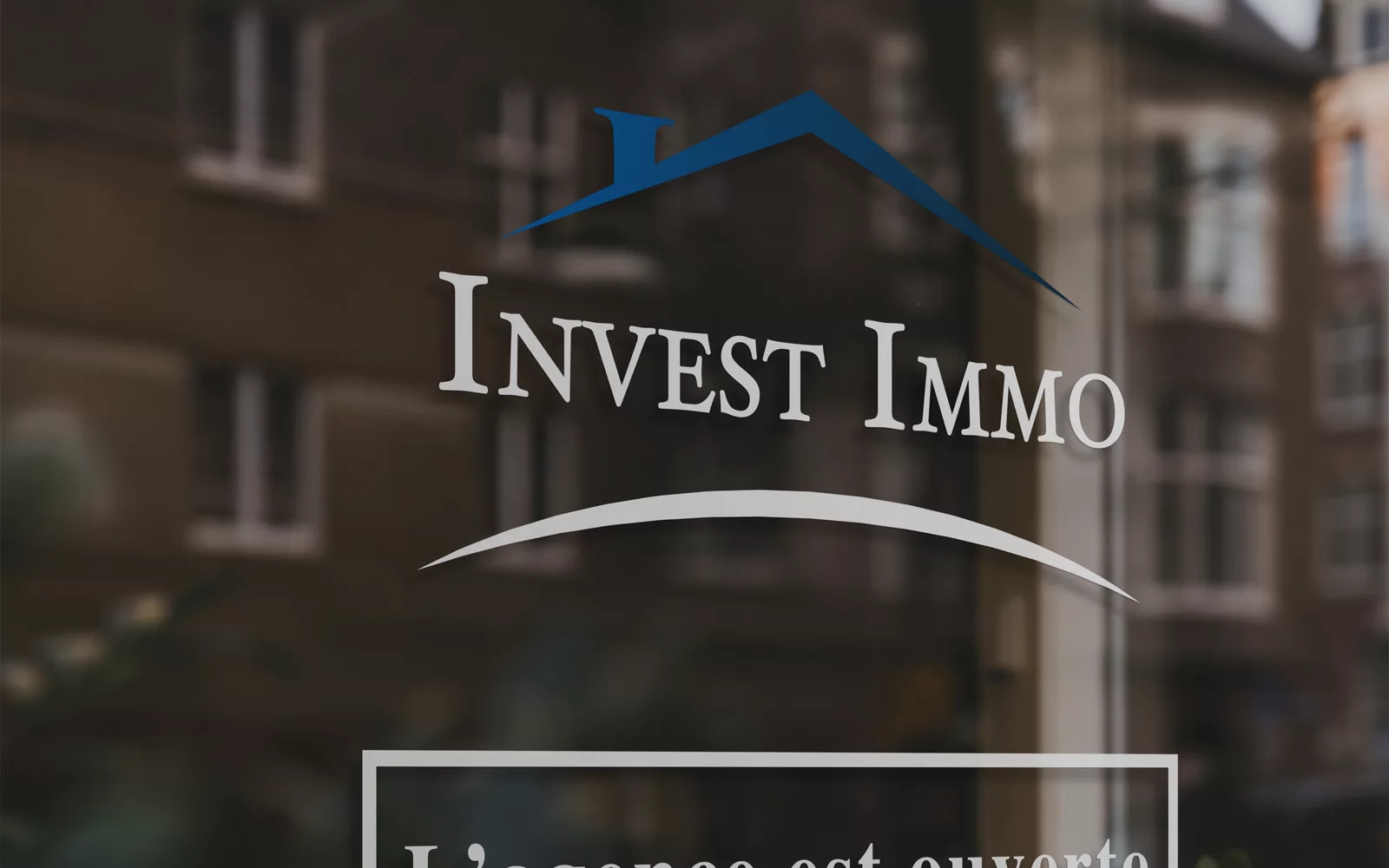 Logo Invest Immo appliqué sur une vitrine d’agence immobilière